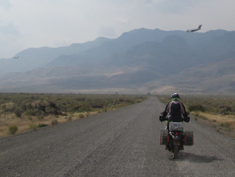 Jayne riding her motorcycle with military transport planes in the distance.