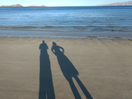 shadows of a man and a woman on the beach